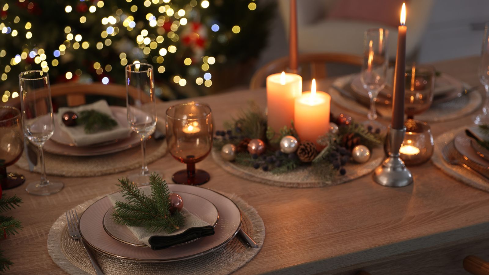 Mesa servida con velas y decoración navideña, lista para una cena de empresa de fin de año