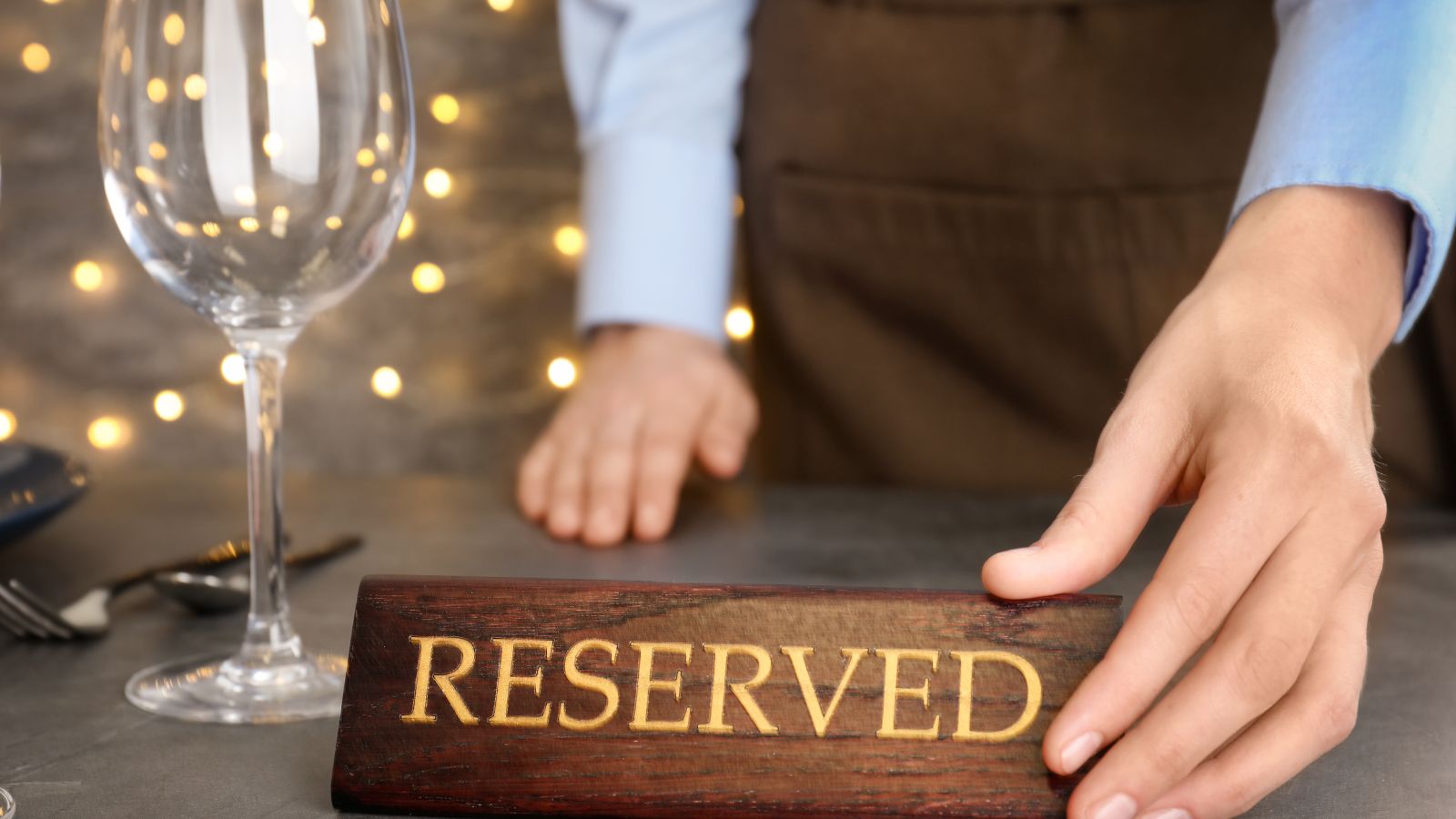 Garzón poniendo un cartel de mesa reservada en un restaurante