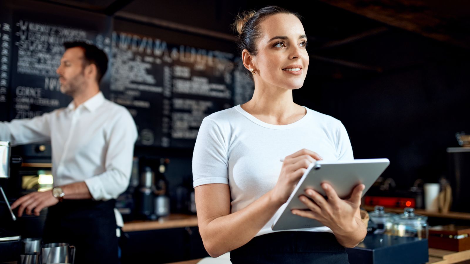 Datos de clientes en un restaurante, trabajadora de una cafetería revisando información en una tablet