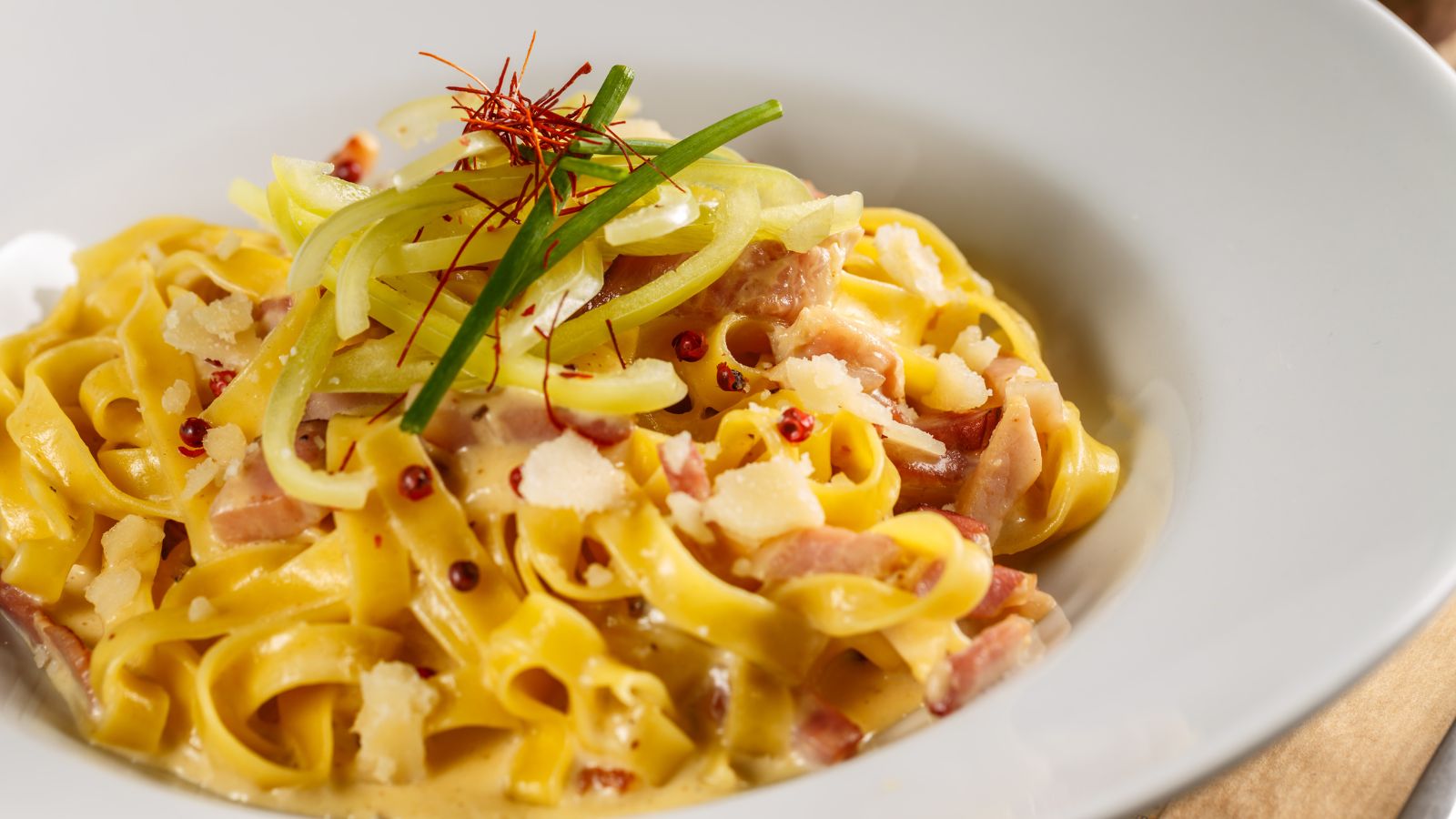 Plato de fettuccine con salsa cremosa, tocino y queso rallado en un restaurante