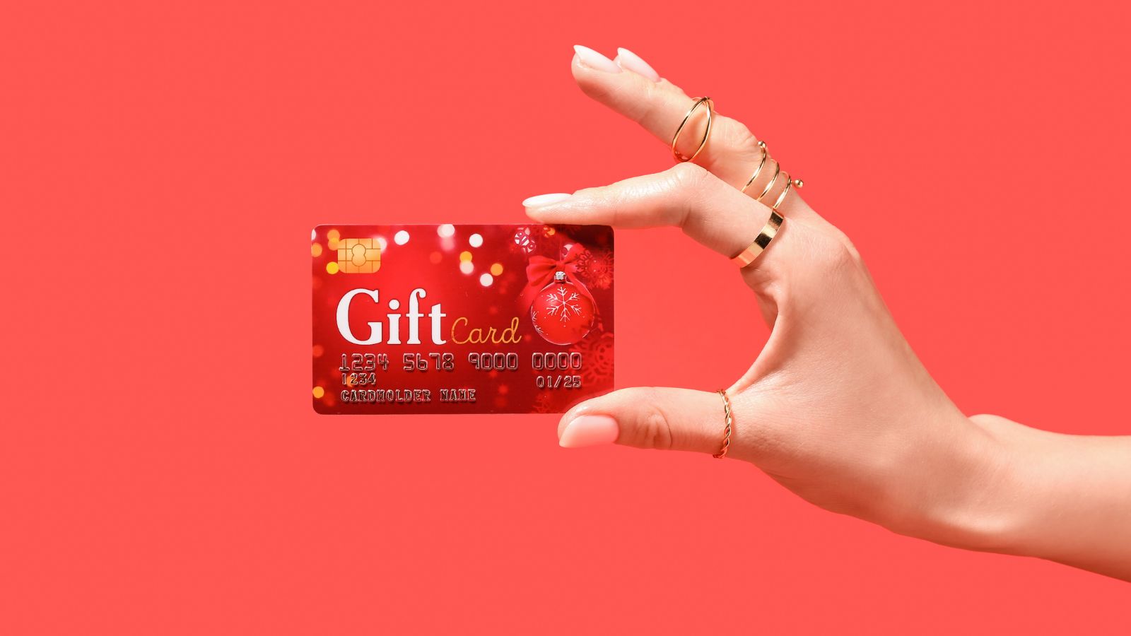 Mano sosteniendo una gift card navideña roja sobre fondo rojo