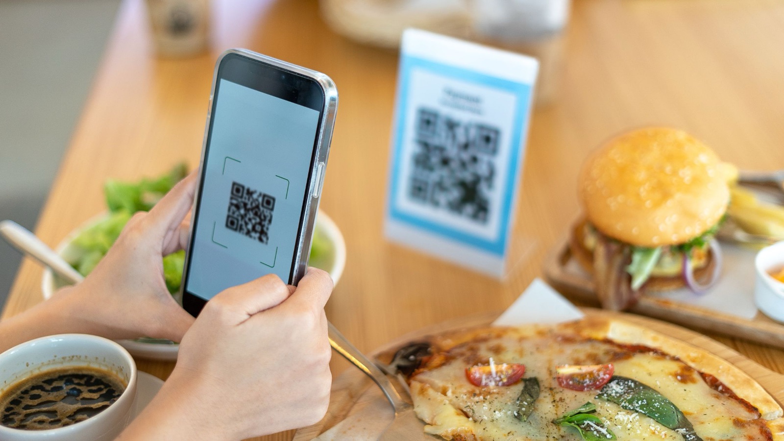 Clienta escaneando el menú digital con QR desde la mesa de un restaurante
