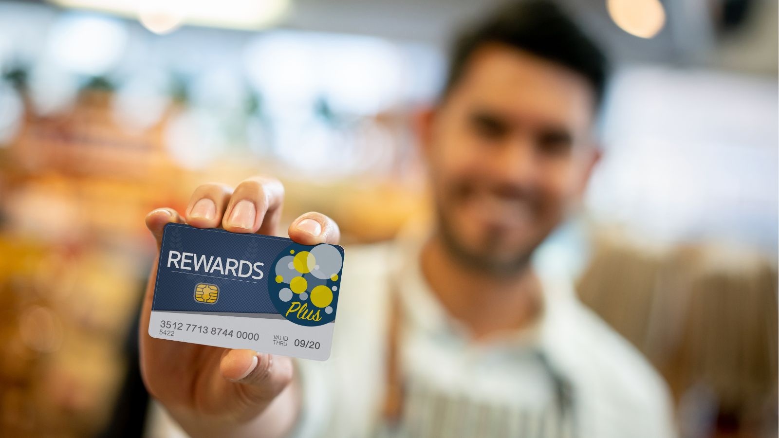 Niveles de fidelización, trabajador de una cafetería muestra una tarjeta de recompensas a la cámara