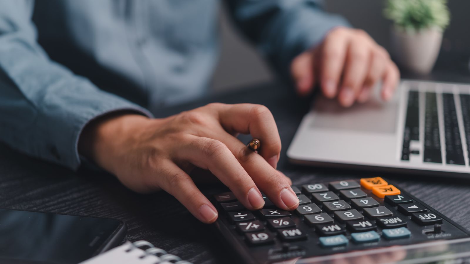 Presupuesto 2027 para restaurantes, manos usando una calculadora junto a un notebook sobre un escritorio