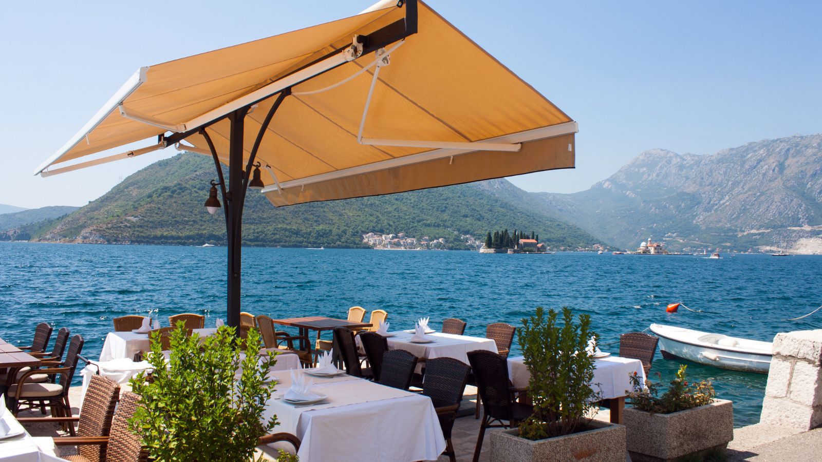 Terraza de restaurante con mesas servidas frente al mar en verano